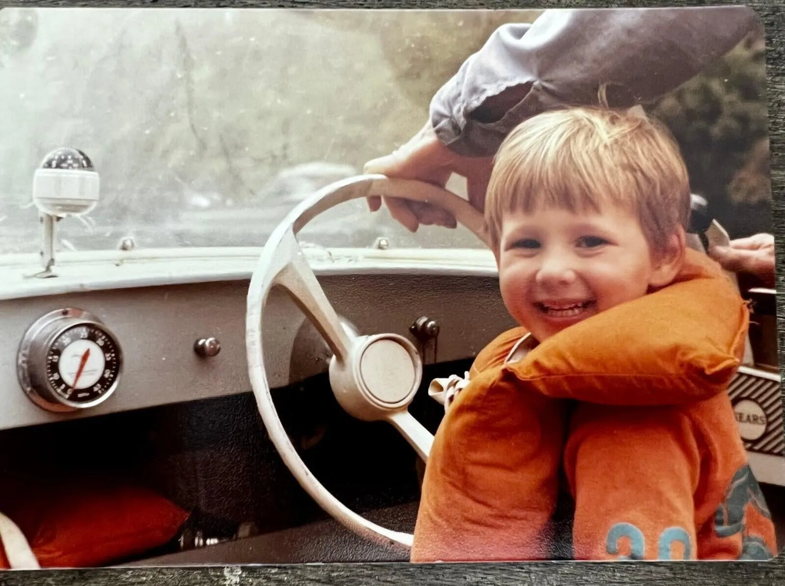 Domonic as a child at a boat helm